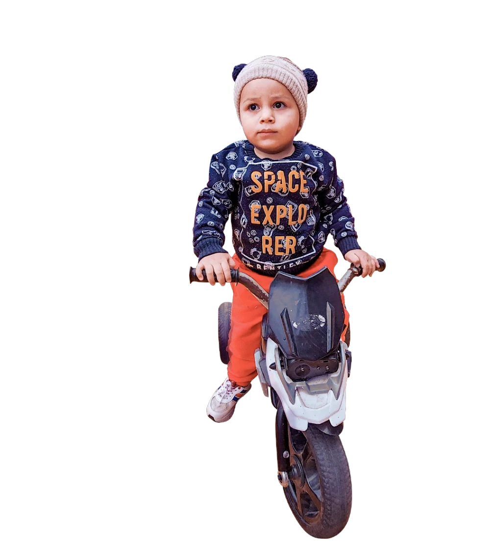 Niño con casco sobre una moto de juguete