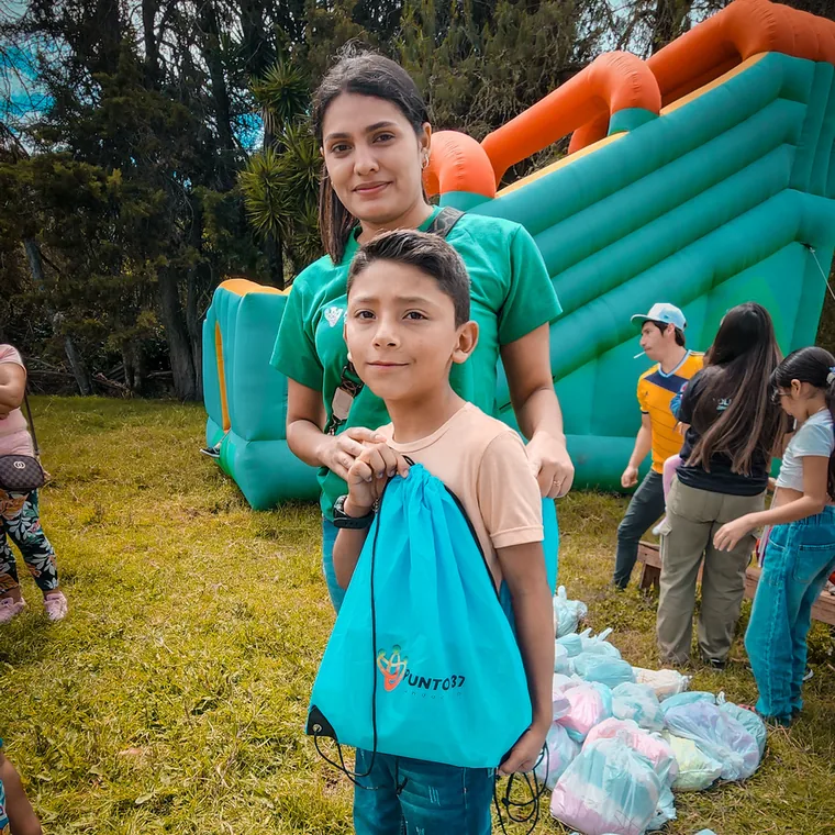 Voluntaria y niño con un morral de la fundación en una jornada social